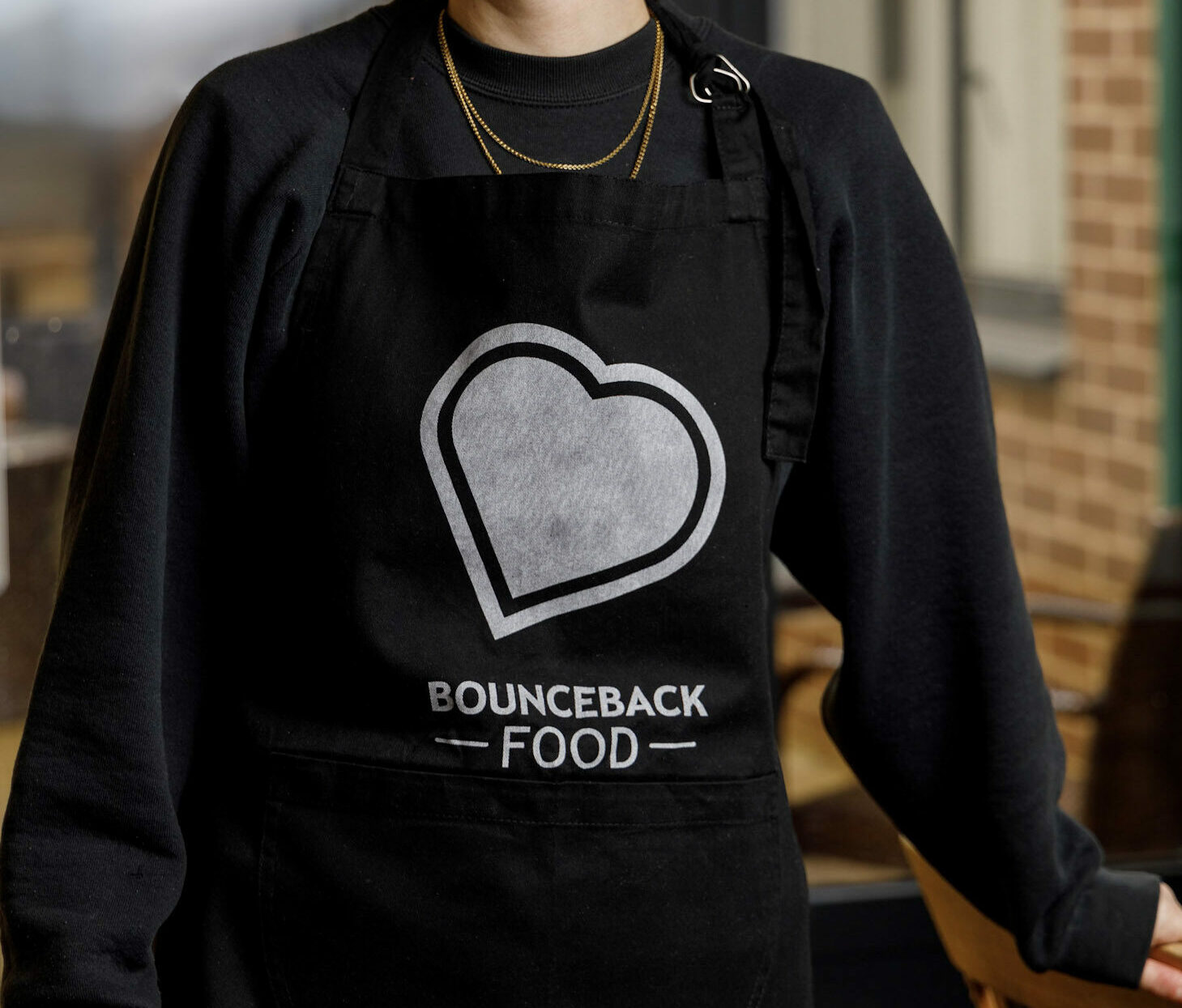 An adult wearing a Bounceback Food CIC Apron