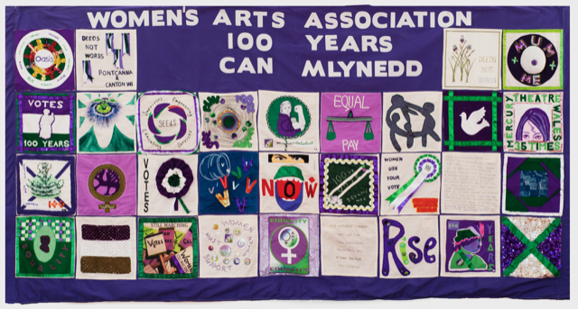 Artwork by members of Women's Arts Association Wales displayed together on a patchwork quilt.