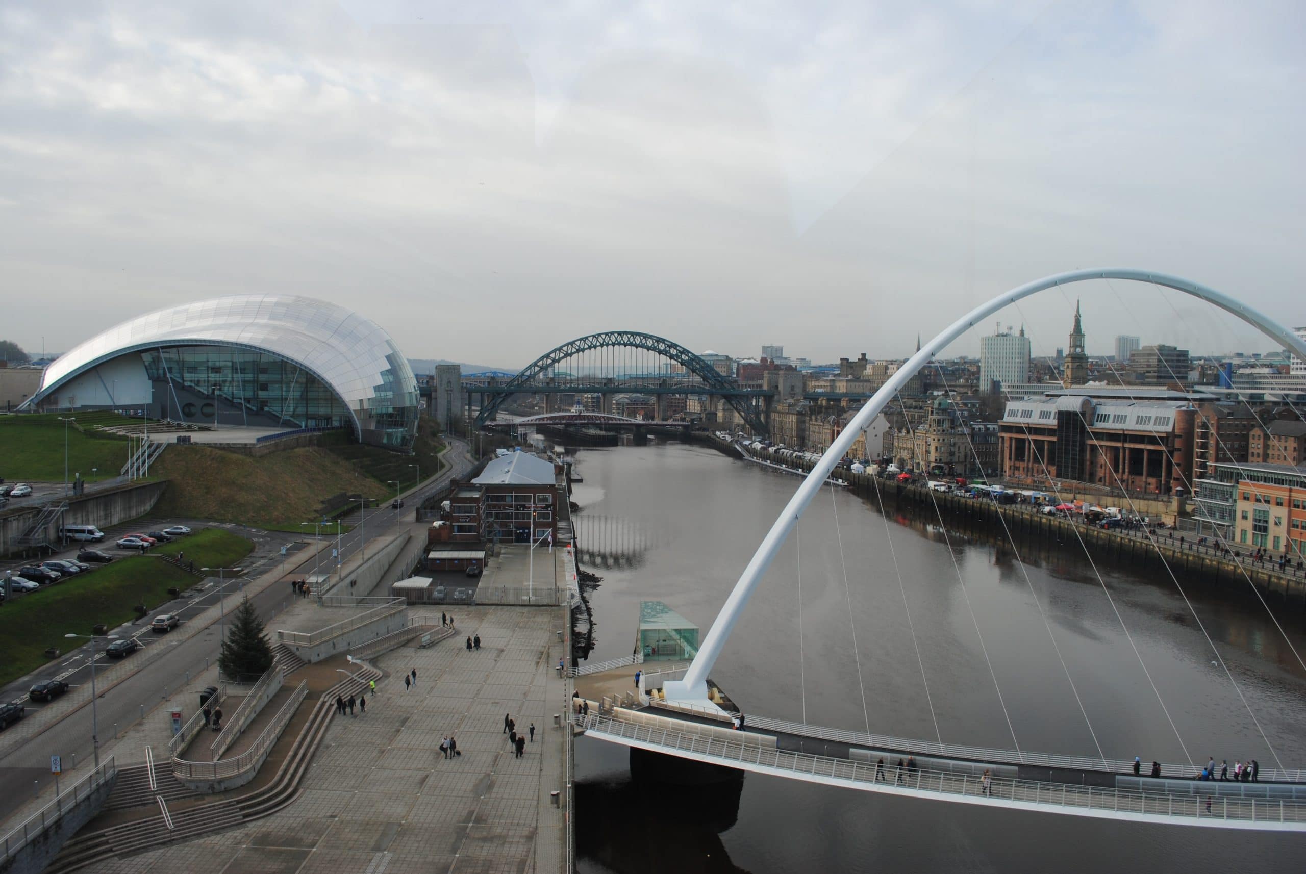 The riverside that separates Newcastle and Gateshead on a cloudy day, with two bridges in clear view.