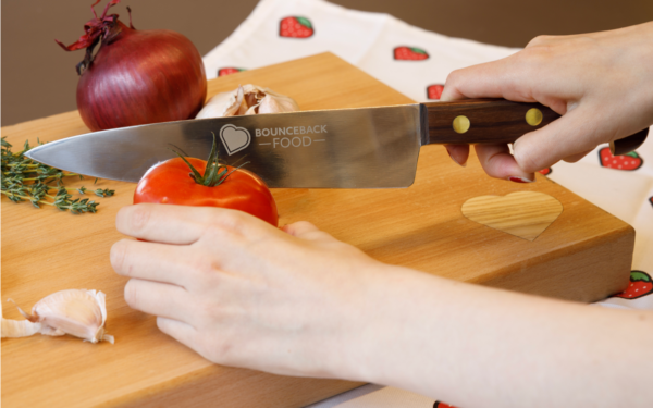 A knife is slicing through a wooden chopping board with the Bounceback logo in the bottom right corner.